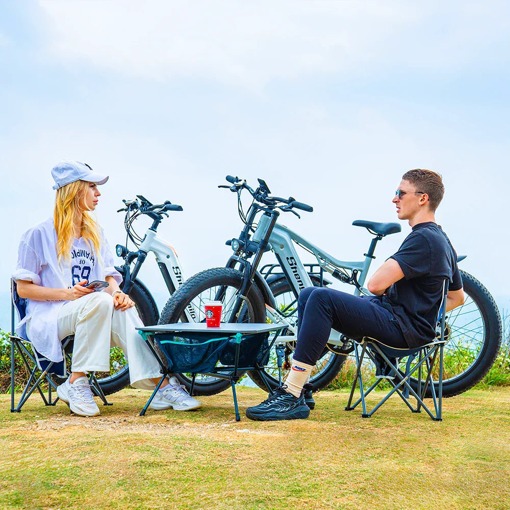 The Ultimate Electric Bike for Power Range & Style shown with two people relaxing outdoors beside Shengmilo S600 e-bikes